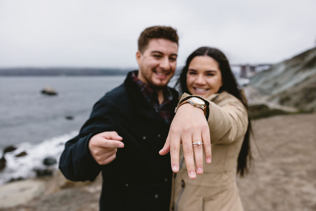 Newly engaged couple showing off engagement ring on Bakers Beach in San Francisco California after planning for proposal in secret