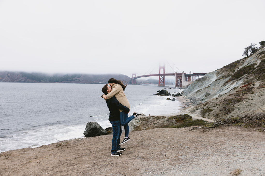 Newly engaged couple kissing on Bakers Beach in San Francisco California