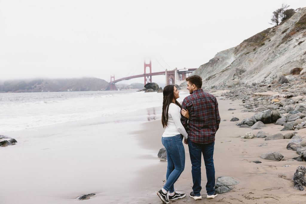 Newly engaged couple posing for photos on Bakers Beach in California 
