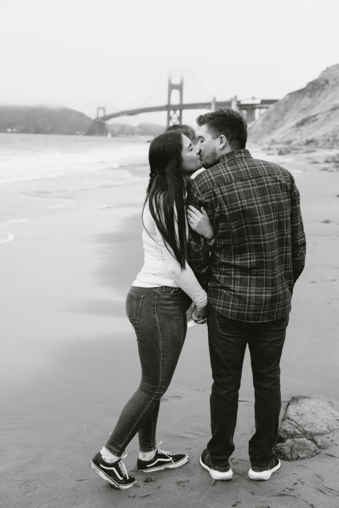 Newly engaged couple kissing and posing for photos on Bakers Beach in California 