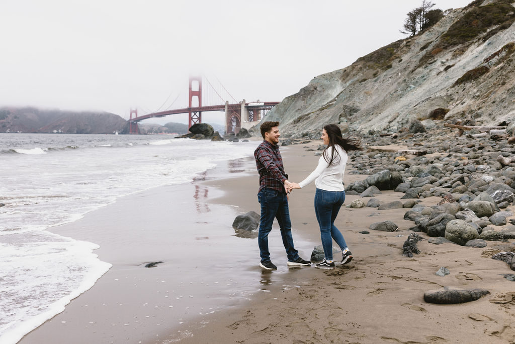 Newly engaged couple posing for photos on Bakers Beach in California 