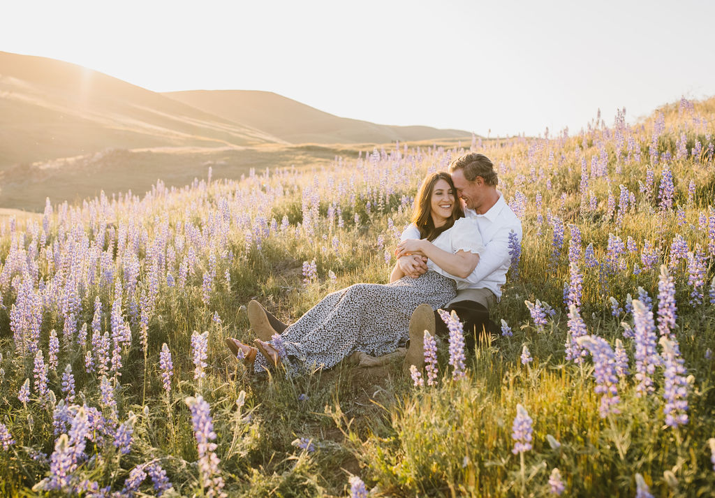 Man and women sitting in a wildflower field for engagement session