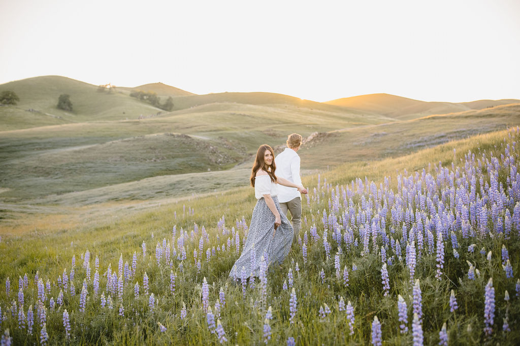 Man and women walking through wildflower field for engagement session