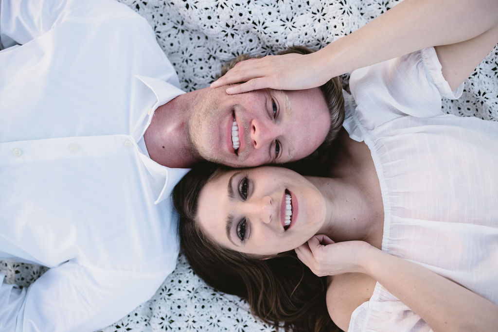 Man and woman laying on a blanket during romantic engagement session in Fresno CA