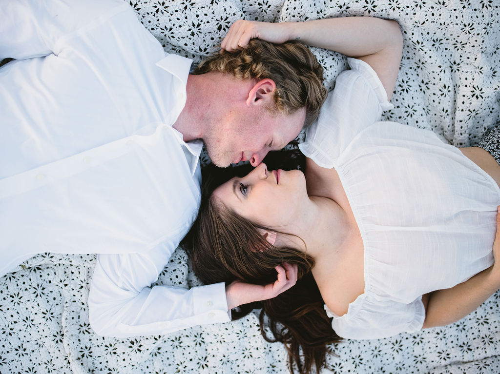 Couple laying on a blanket side by side during photoshoot