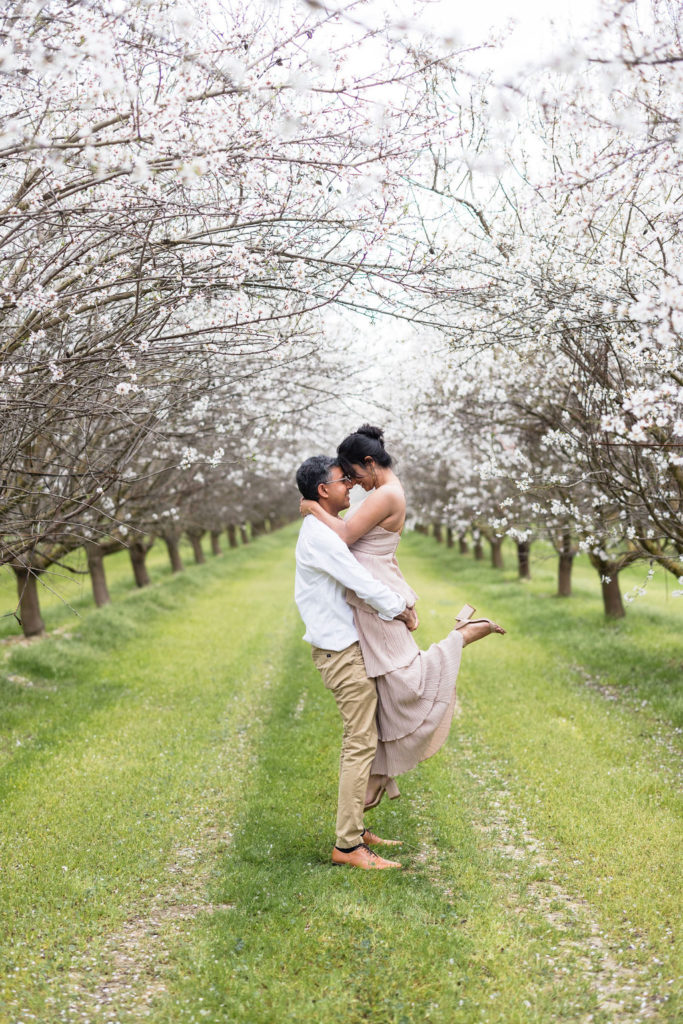 Couple posing for engagement photos in The Almond Orchards in Fresno, California