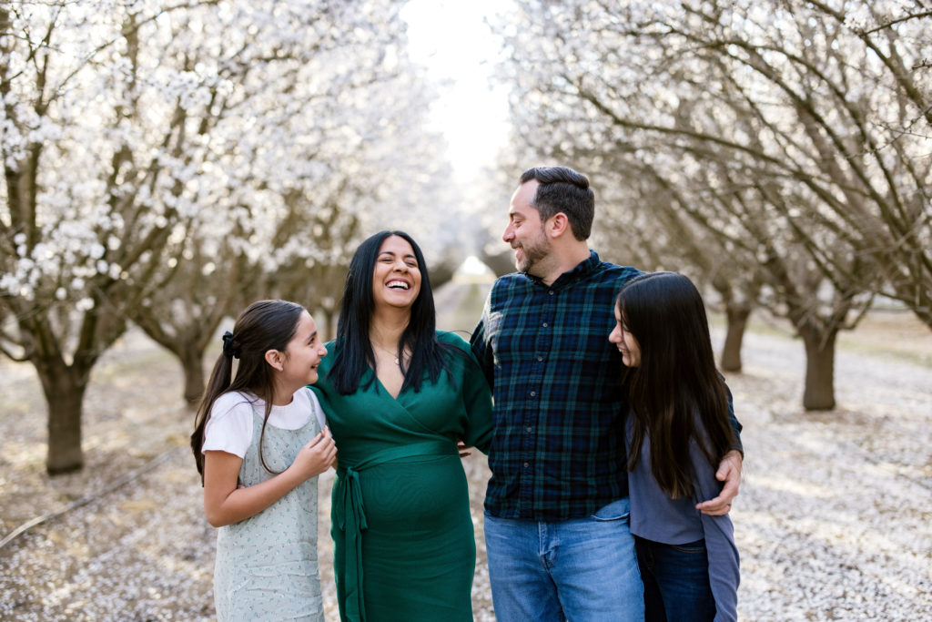 Family posing in almond blossom orchard