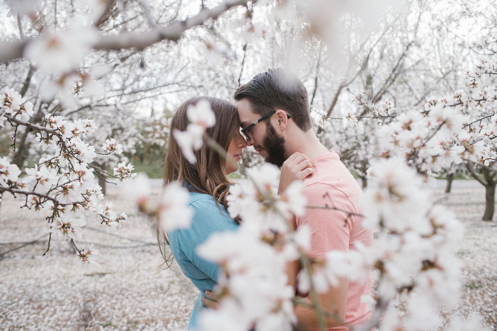 Couple posing for engagement photos in The Almond Orchards in Fresno, California