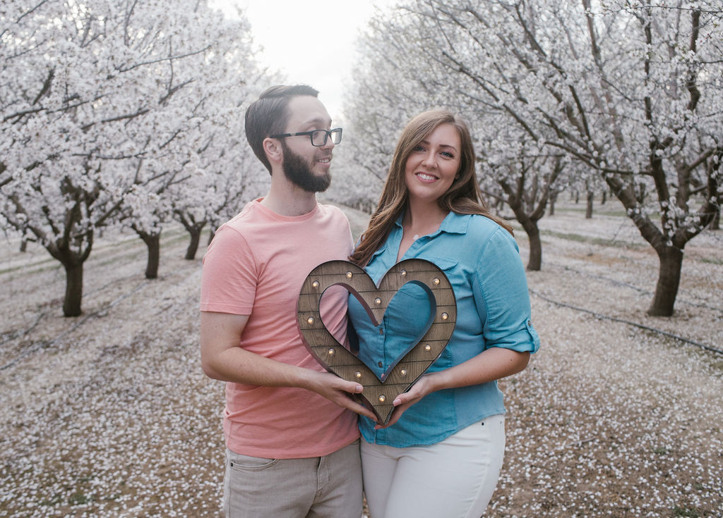 Couple holding wooden heart during engagement session