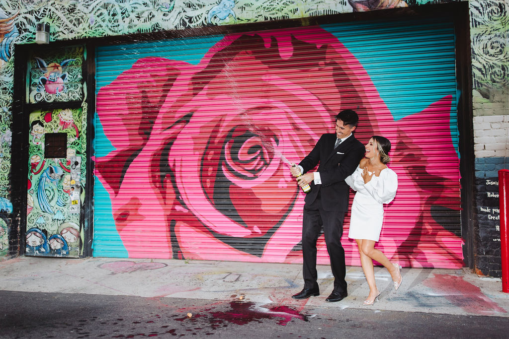 Bride and groom posing in front of wall art in Fresno, CA
