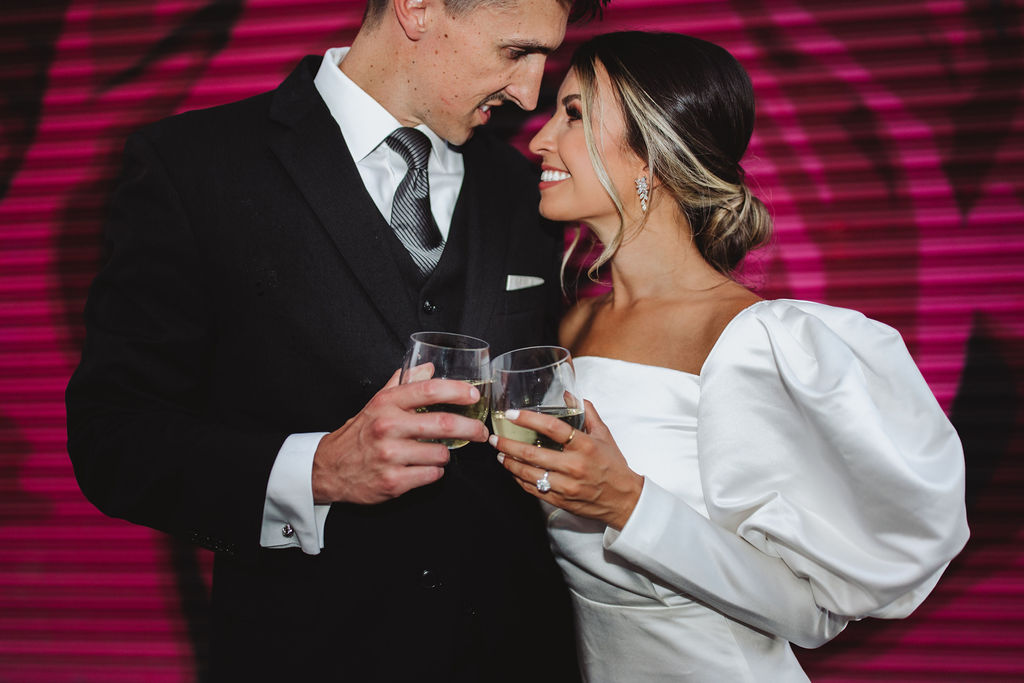 Bride and groom toasting in front of colorful backdrop