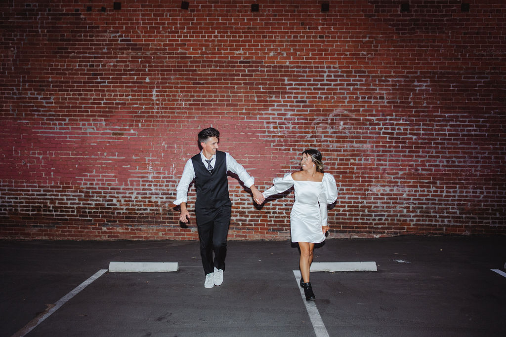 Bride and groom in front of brick wall in Fresno, CA