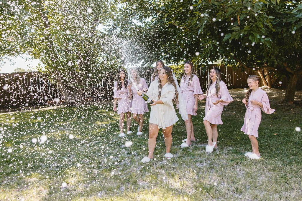 Bride and bridesmaids popping champagne 