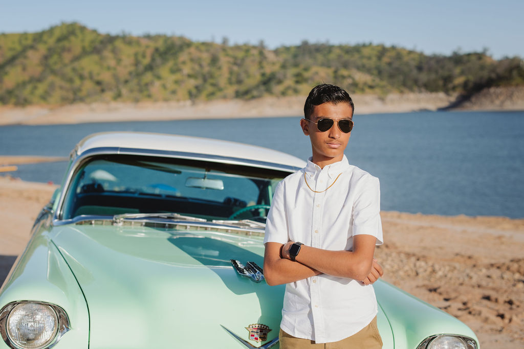 Boy posing in front of vintage car