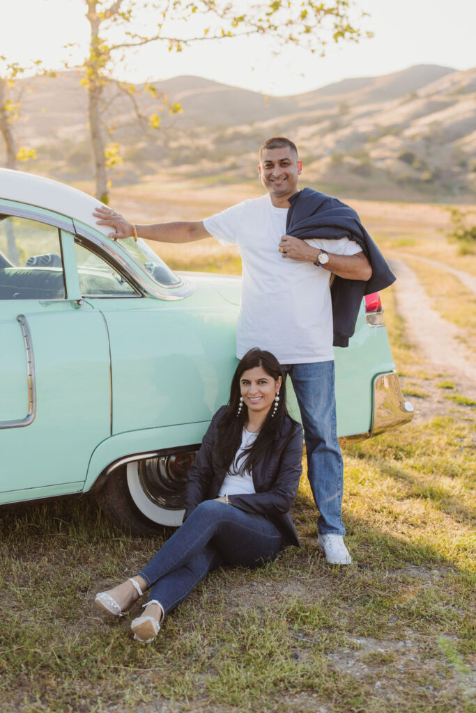 Couple posing for photos next to vintage car