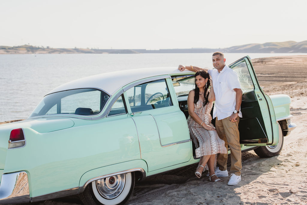 Couple posing for photos with a vintage car