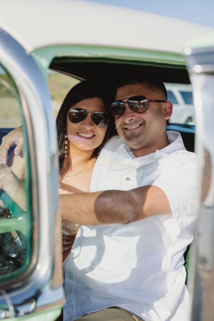 Couple posing for photos inside a vintage car