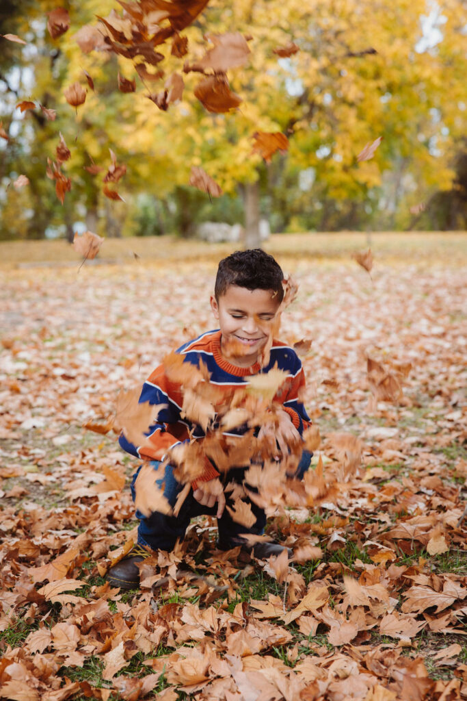 Little boy playing with the fall leaves