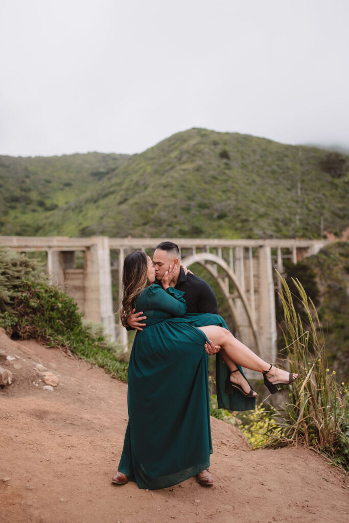 Couple posing for Big Sur engagement photos by Bixby Bridge