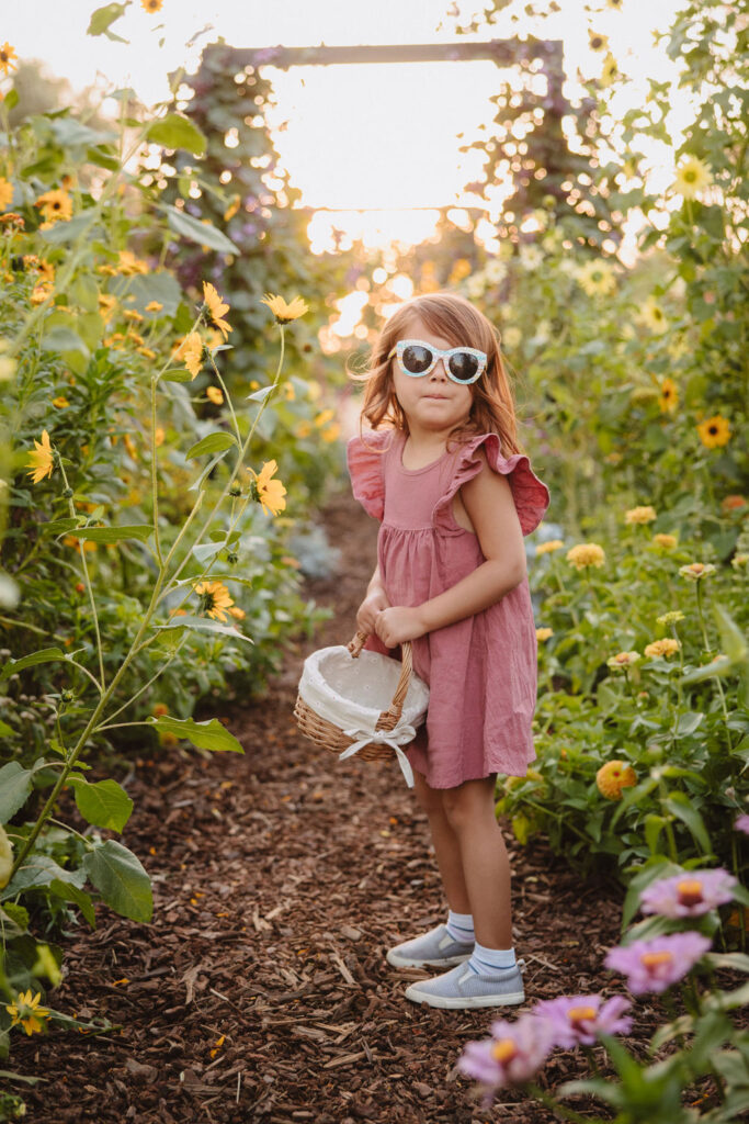 Little girl with sunglasses walking in a flower field