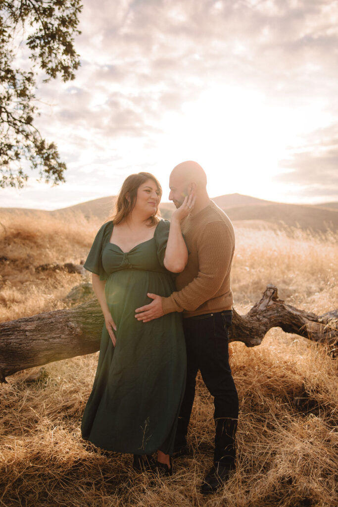 Man and pregnant woman in a field during sunset