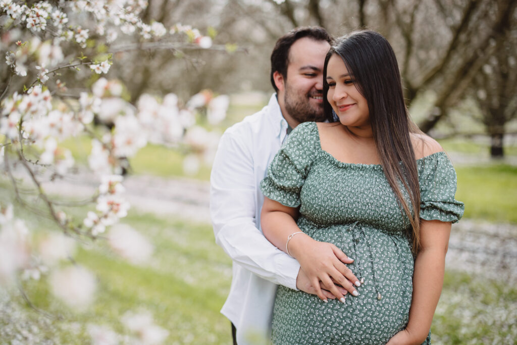 Couple posing during their maternity session in almond orchards in fresno ca