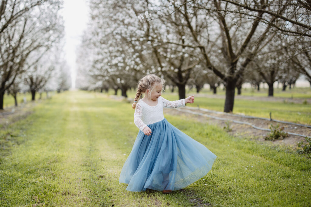 Little girl twirling in Almond orchard in Fresno Ca