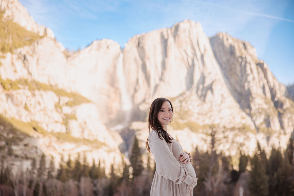 Pregnant woman holding her belly in front of half dome
