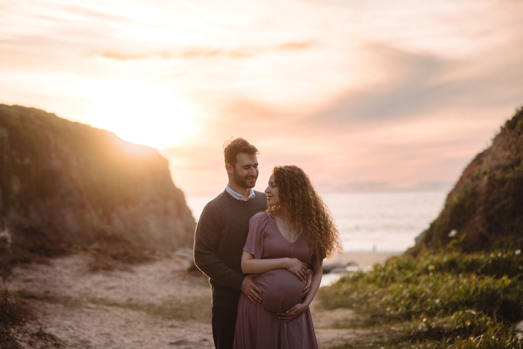 A couple at the beach at sunset, with flowers and a pathway in the foreground at Big Sur