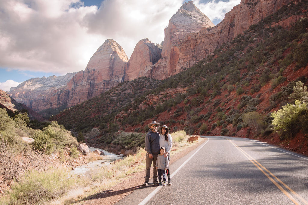 A family standing on a road with a scenic mountain backdrop in zion national park.
