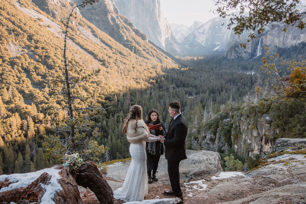 A couple exchanging vows at an outdoor wedding ceremony with a scenic mountain valley backdrop at Yosemite National Park