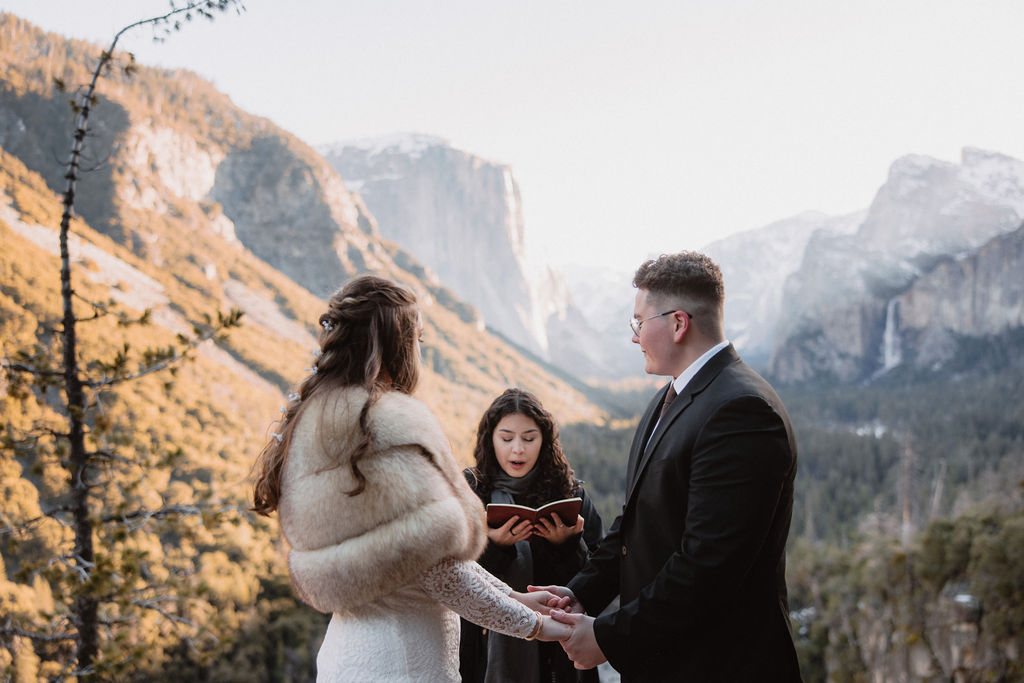 A couple exchanging vows at an outdoor wedding ceremony with a scenic mountain valley backdrop at Yosemite National Park