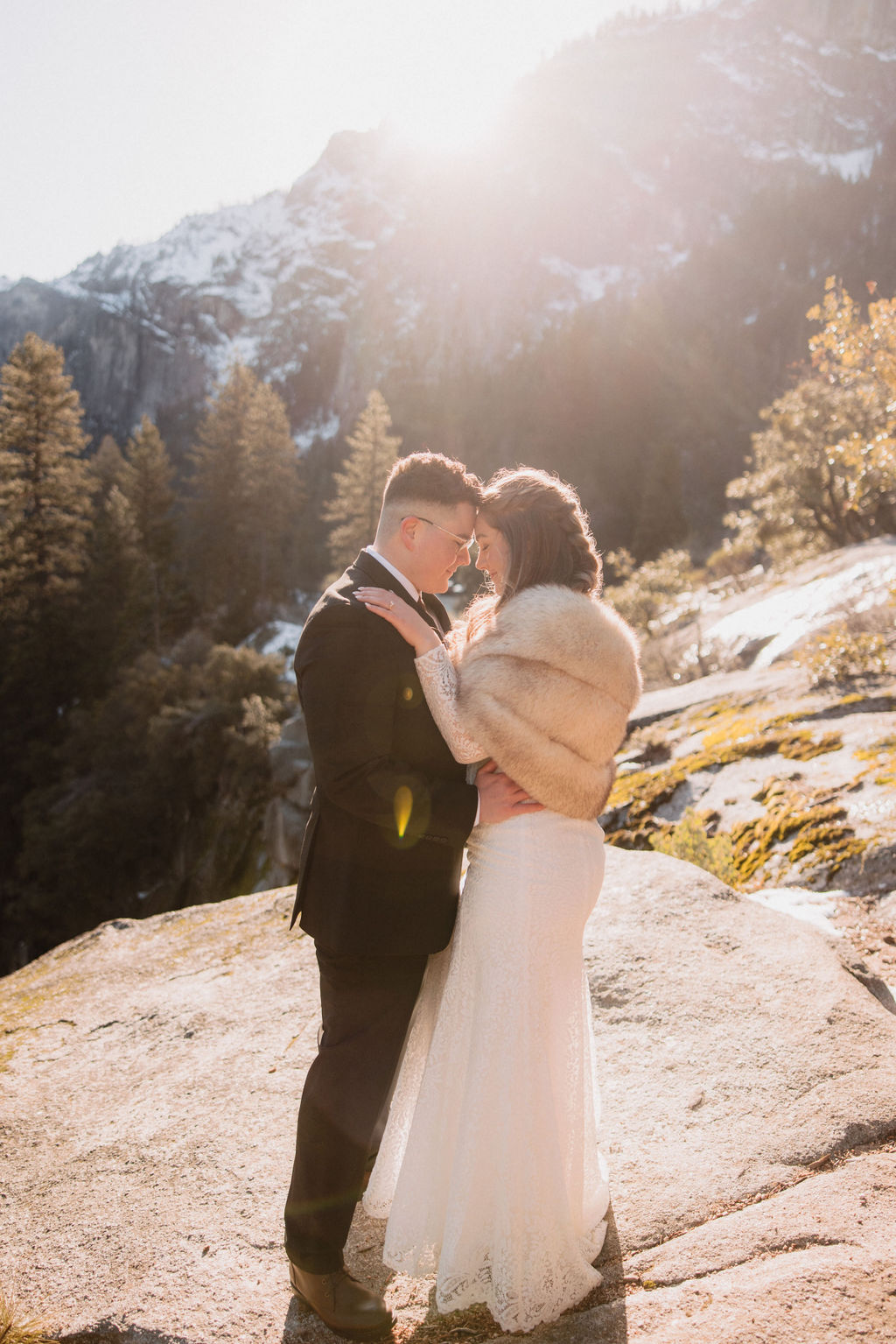 A couple in wedding attire dancing on a mountain overlook with scenic cliffs in the background.