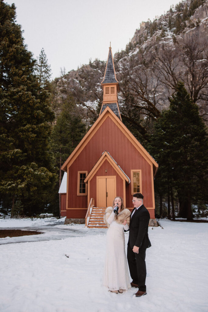 Couple embracing in the snow in front of Yosemite chapel a beautiful elopement location