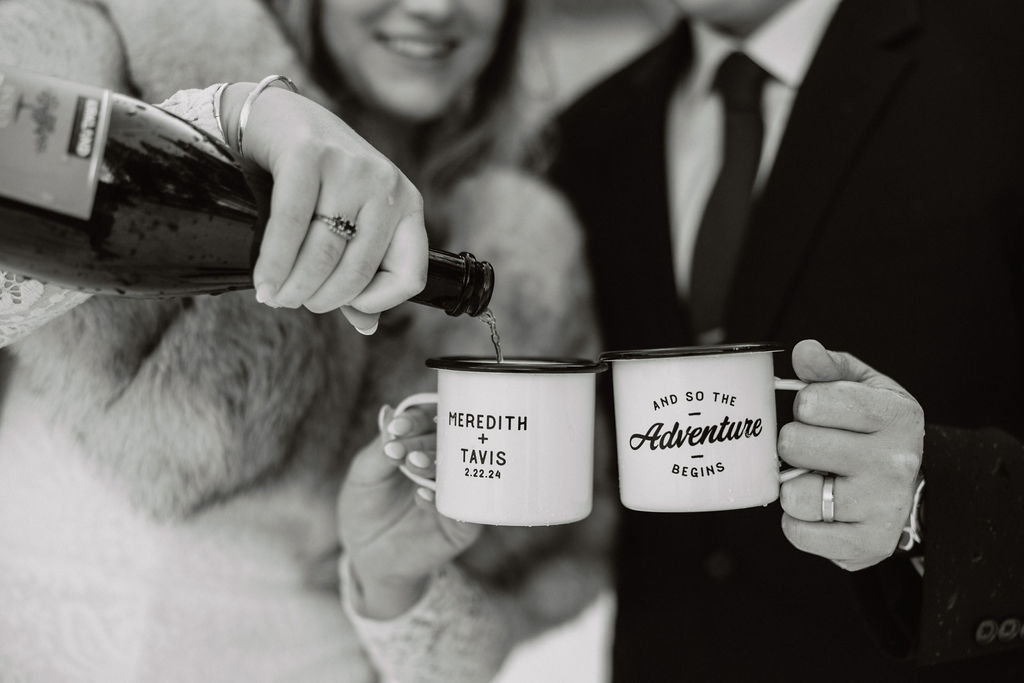 Pouring a celebratory drink into personalized mugs for a wedding toast.