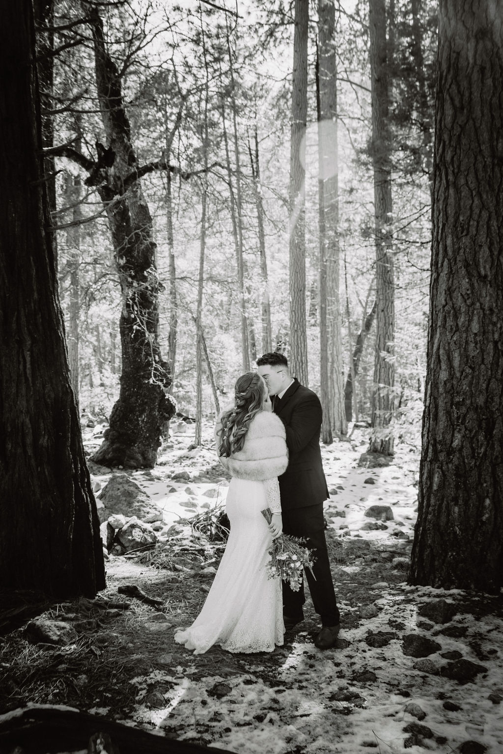 A couple embracing in a snowy forest setting at Yosemite National park.