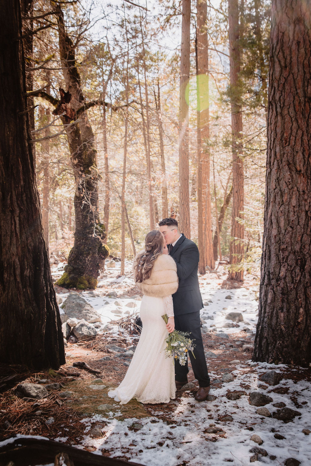 A couple embracing in a snowy forest setting at Yosemite National park.