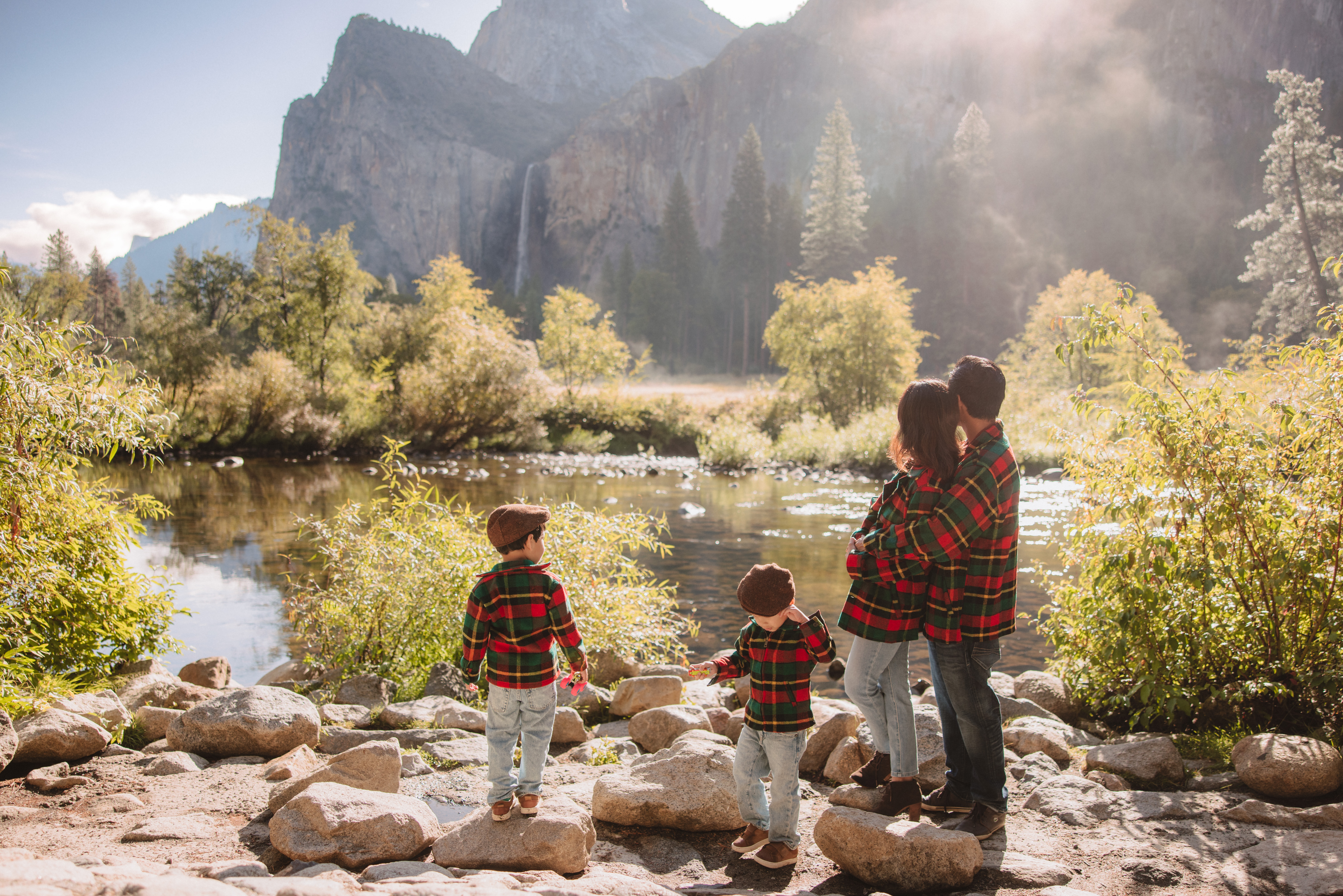 Family relaxing at the river at valley view in yosemite during their family photoshoot. 