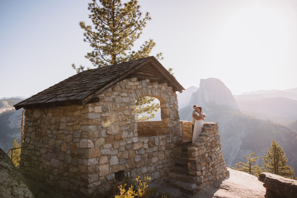 Couple holding each each other on a brick house at glacier point in yosemite at sunrise. 