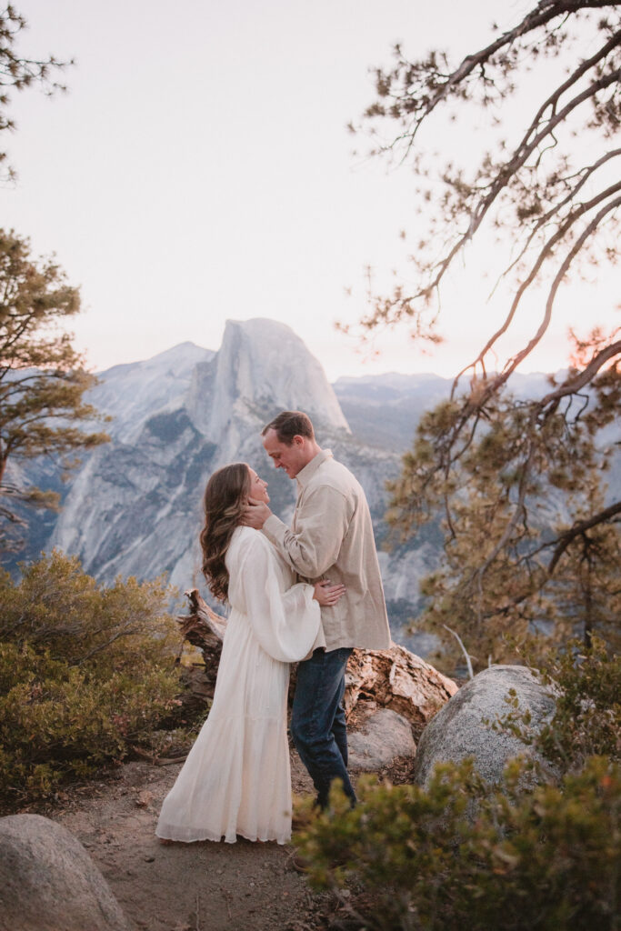 Couple embracing each other before sunrise at glacier point in yosemite during their engagement photosoot. 