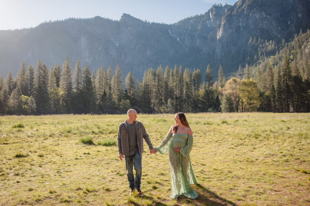 Maternity couple walking on el cap meadow in yosemite during their maternity photoshoot. 