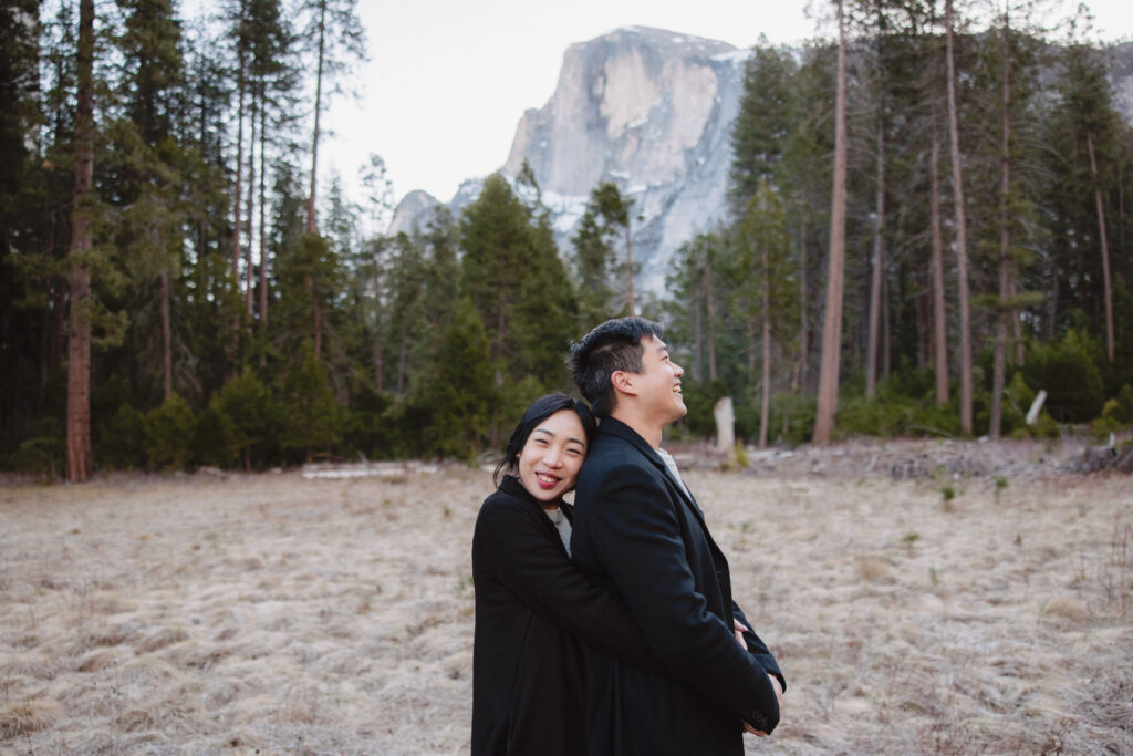 Couple embracing each other during their engagement photoshoot at half dome meadow in yosemite. 