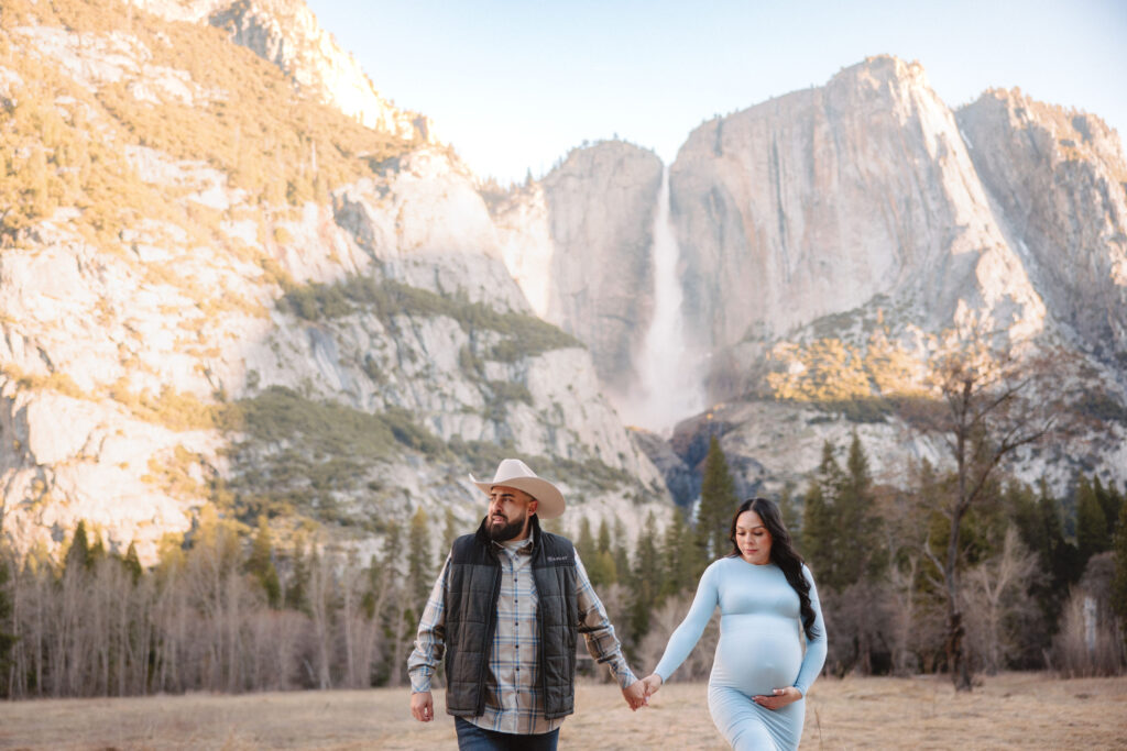 Maternity couple walking at swinging bridge meadow during their photoshoot. 
