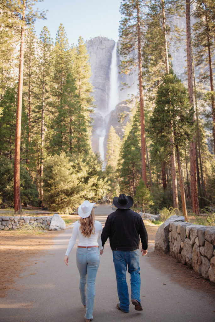 Couple walking toward yosemite falls in the spring during their engagement photoshoot. 
