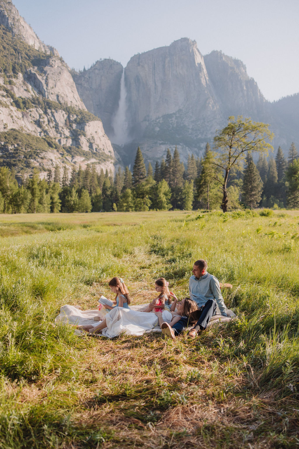 Family at Yosemite National park for their documentary style family photos walking into meadow and setting up a picnic