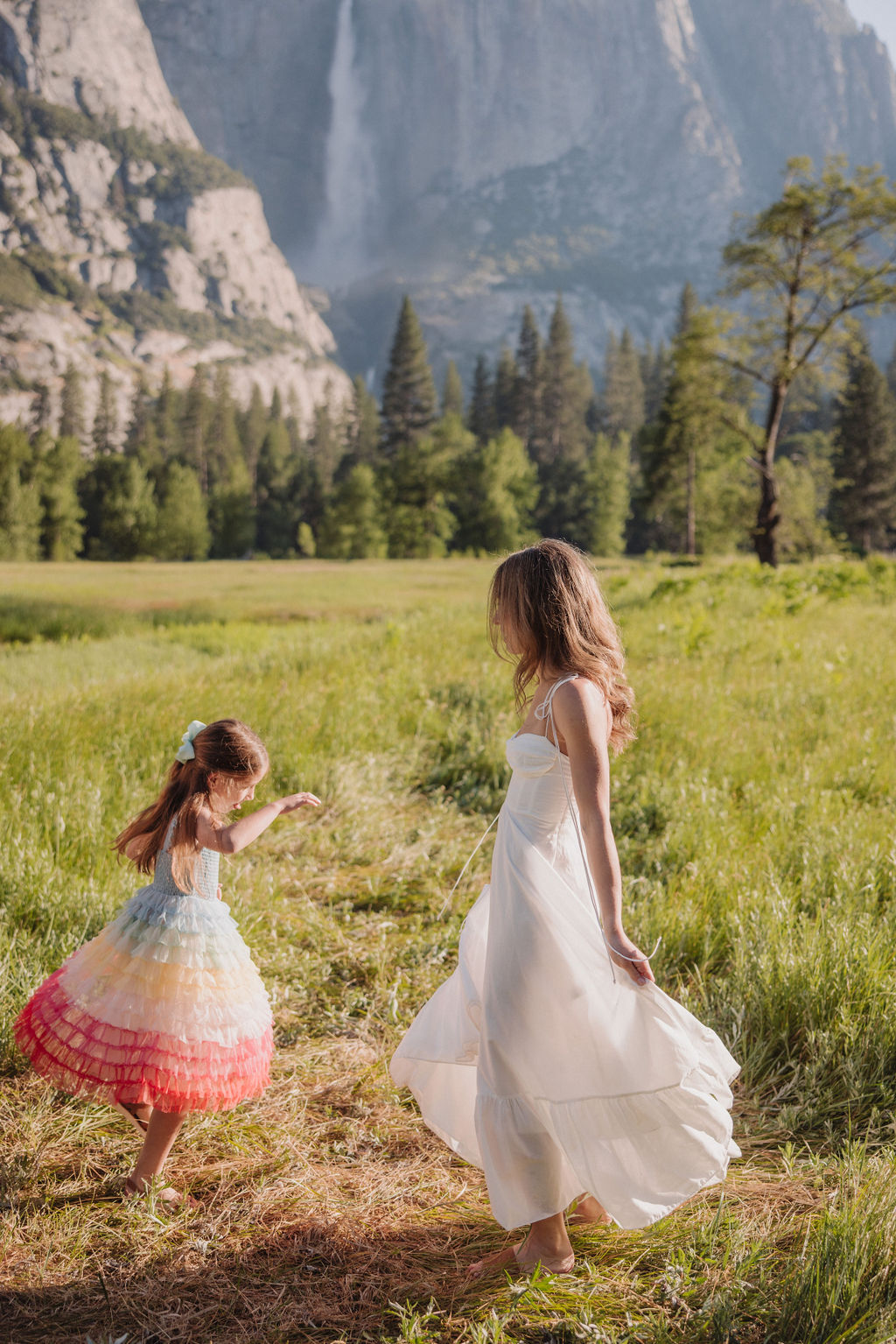 Family at Yosemite National park for their documentary style family photos walking into meadow and children running around with their mom