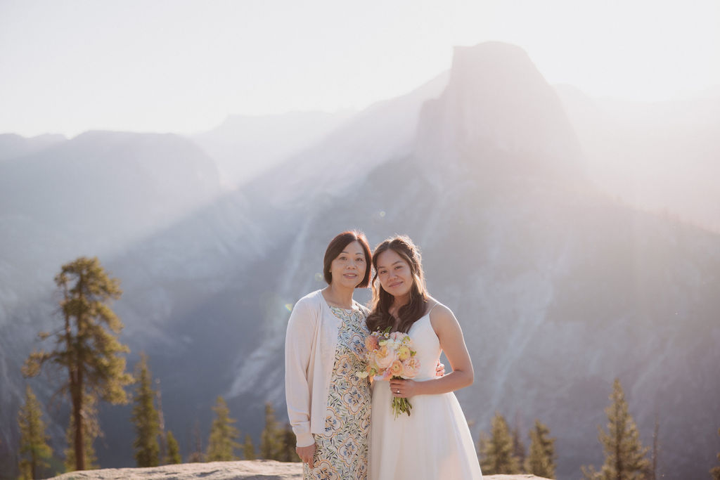 A group of six people, including a bride and groom, pose together outdoors with mountains in the background in Yosemite for an elopement