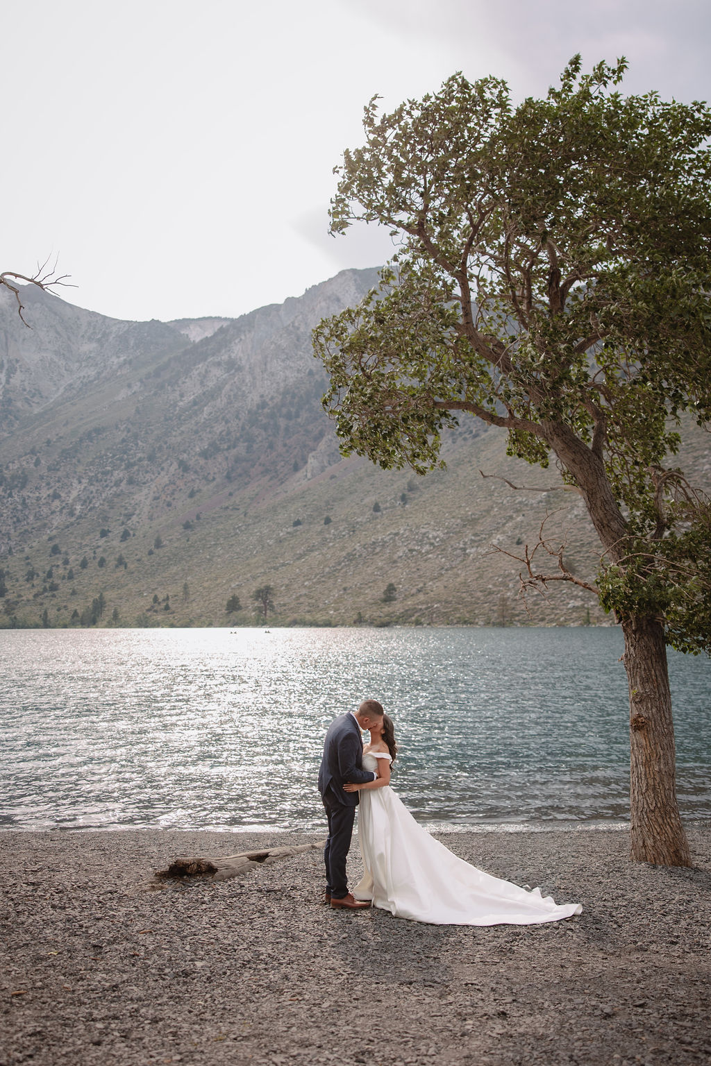 A wedding ceremony by a lakeside, with a couple in formal attire and a man officiating for a mammoth lakes elopement