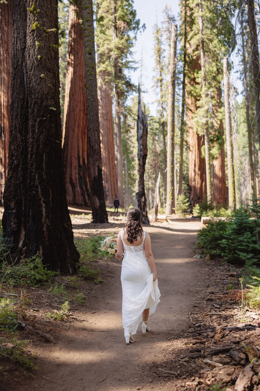 A person in a white dress walks along a forest trail surrounded by tall trees.
Top 5 reasons to elope in sequoia national park
