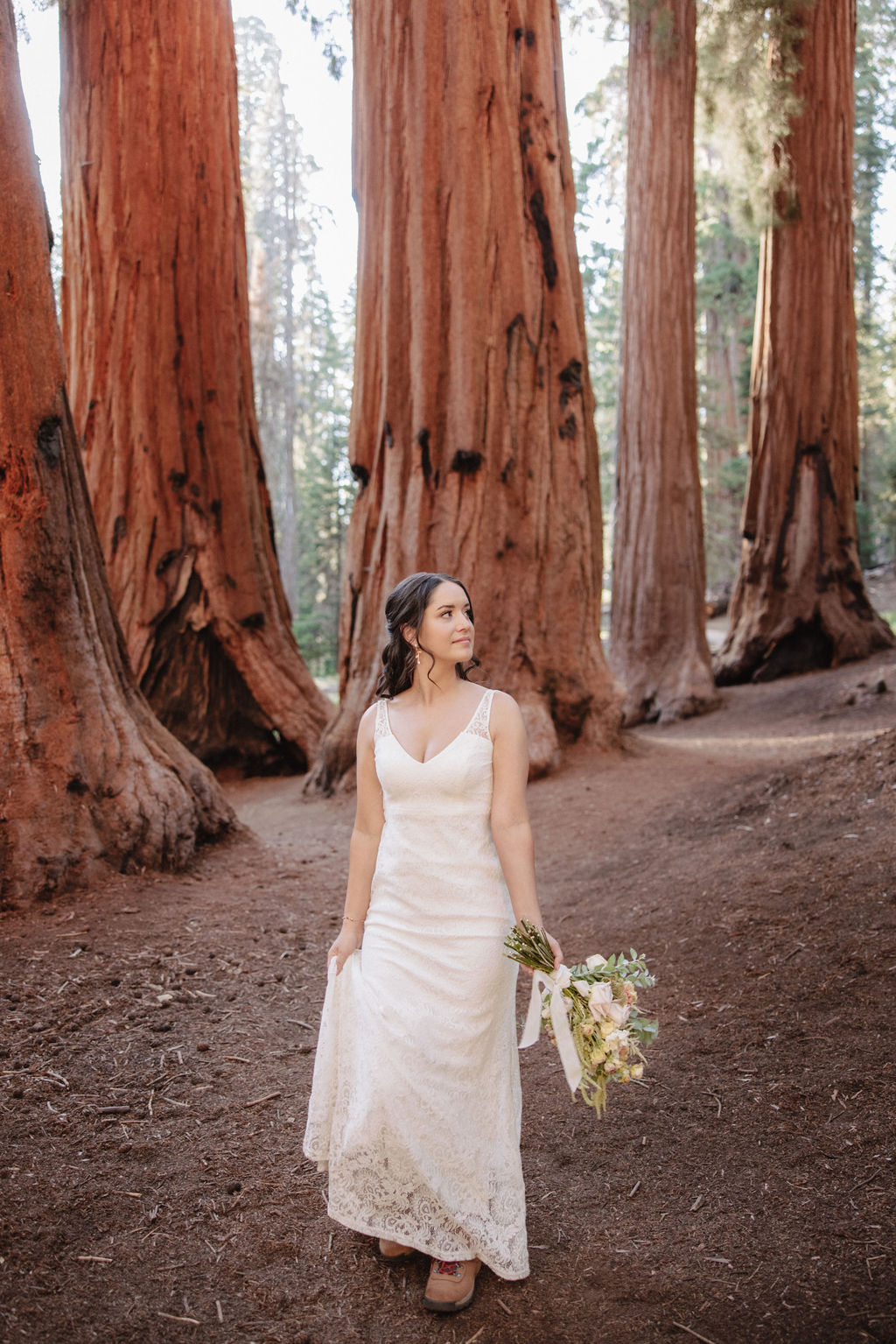 A bride in a white gown holds a bouquet while standing in front of large redwood trees 
Top 5 reasons to elope in sequoia national park